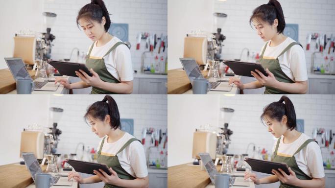 年轻女性烘培师在厨房使用笔记本和平板