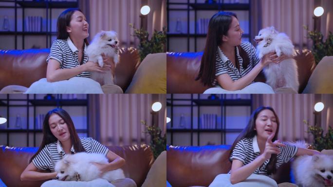 笑容可掬的亚洲女性坐在沙发上拥抱爱犬，与爱犬玩耍，狗主人和奇瓦瓦拉普多普在家度过周末快乐假期
