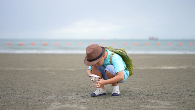 亚洲孩子在海滩上用双筒望远镜和放大镜学习户外运动