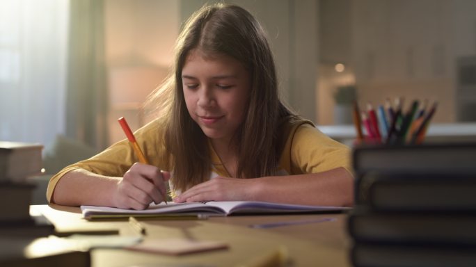 一个年轻女孩独自坐在家里做作业时感到困倦的4k视频片段