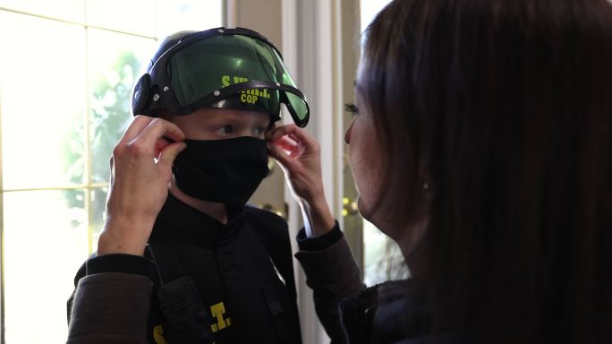 万圣节期间，一个戴着防护面罩、穿着警察服装的小男孩准备玩“不给糖就捣蛋”游戏