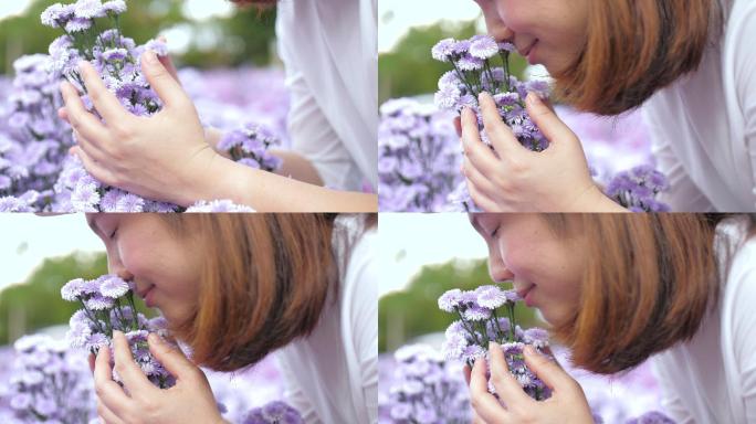 年轻女子幸福地捧着一朵紫花，闻着花园里的紫花