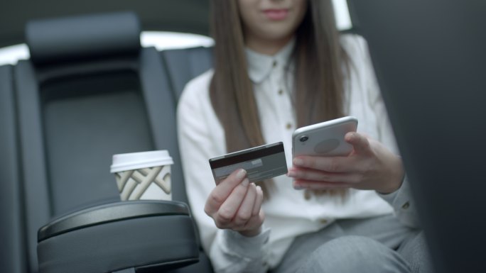 MS年轻女子在众包出租车后座使用智能手机和信用卡