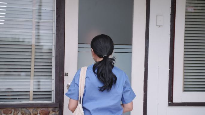 亚洲女护士身穿蓝色制服抵达老年女病人家