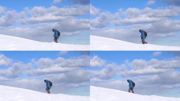 Velika planina，穿着暖和衣服的男人在蓝天下的雪坡上行走