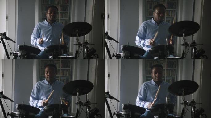 一名非洲裔男子在起居室练习电子鼓。前视图