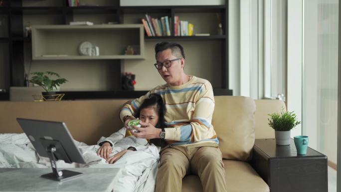 亚洲华人父亲在沙发上为生病的女儿量体温客厅视频通过数字平板电脑与医生通话