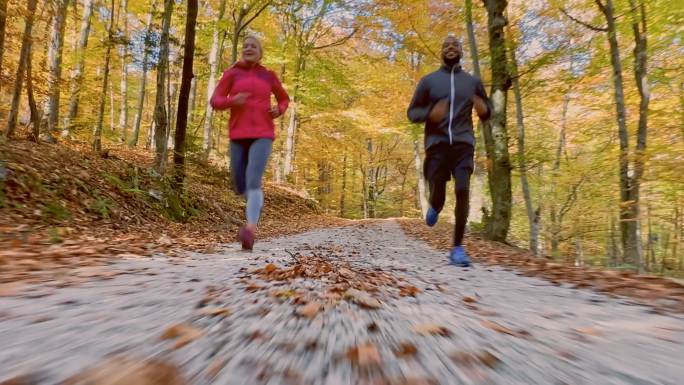 秋天，一对男女沿着森林小道奔跑