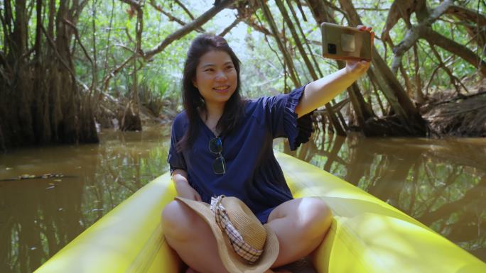 自然旅游活动旅行皮划艇，女性在泥炭沼泽森林湿地划船，亚洲人女性在夏季探索红树林时放松微笑