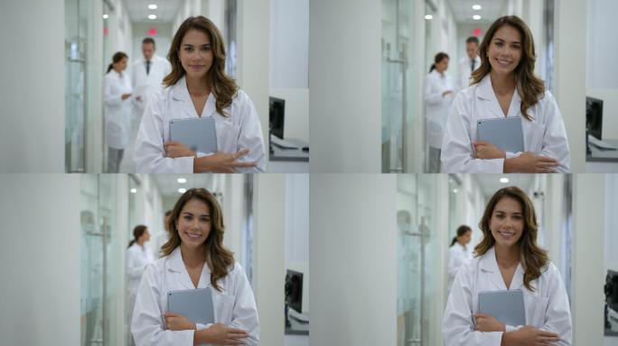 拉丁美洲女医生在医院工作，拿着数码平板电脑微笑着看着摄像机