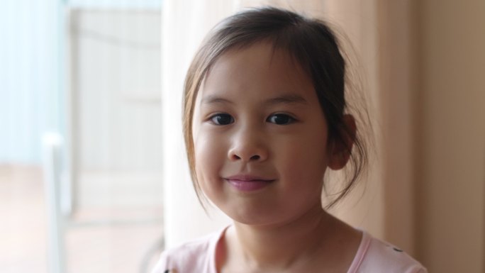 4K慢镜头，快乐的亚裔混血小女孩用手捂住眼睛做心形手势，捐赠、慈善、关怀、爱、心脏健康、社交距离概念