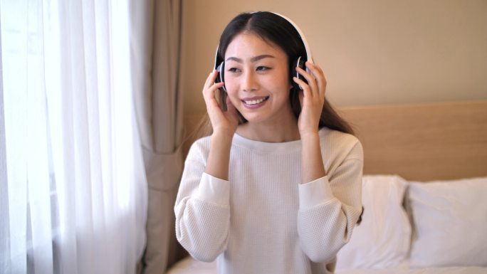 年轻的亚洲女性戴着耳机欣赏音乐