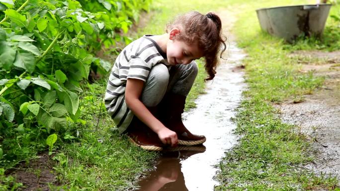小女孩在后院的水坑里玩耍