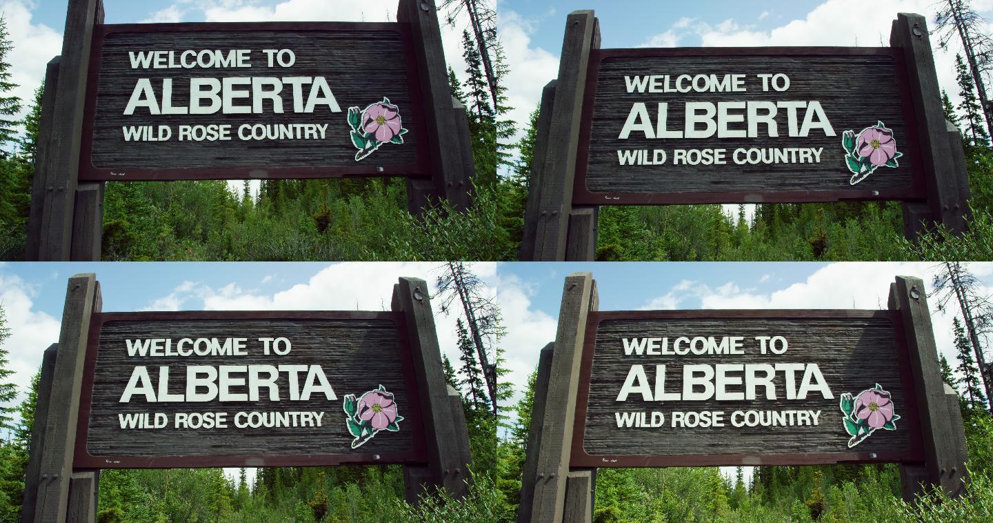 “欢迎来到阿尔伯塔，野生玫瑰之乡”的标志在一个多云的日子里被森林环绕