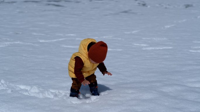 一个蹒跚学步的男孩喜欢在春天的一天在外面的水坑里玩耍