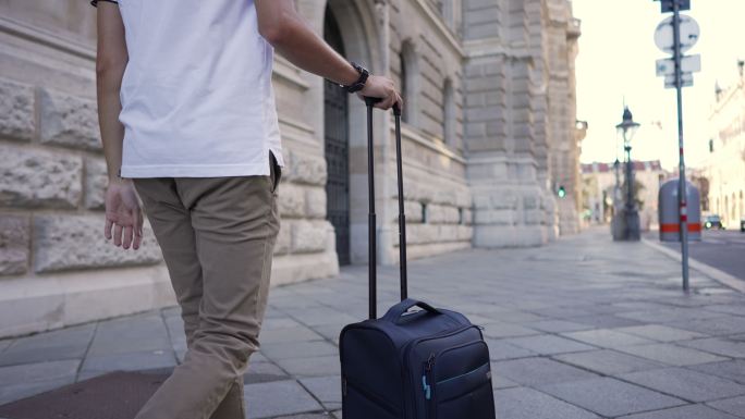 年轻的男性游客，拉着他的手提箱，在探索城市时，他刚刚到达