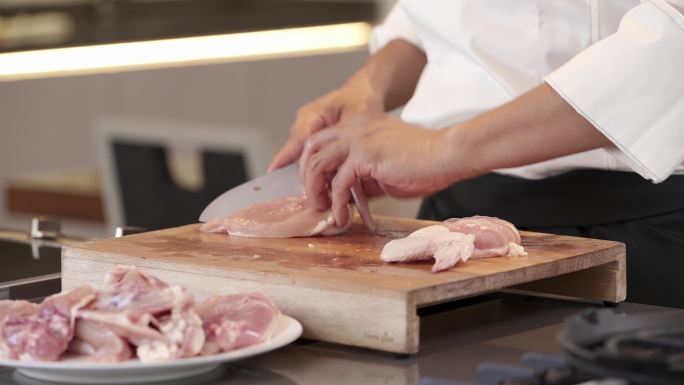 男子用刀将生鸡肉切成块