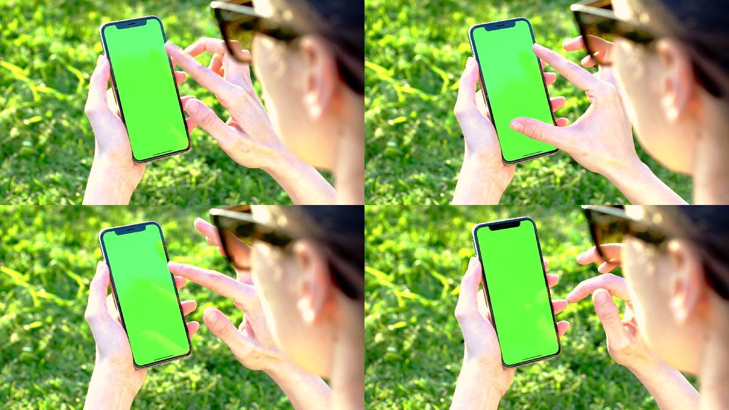 公园内手持手机，绿色屏幕