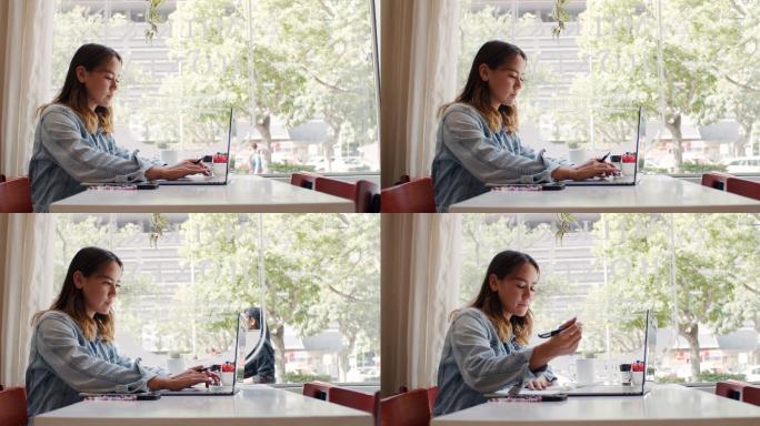 4k视频，一位年轻迷人的女士坐在咖啡馆里使用笔记本电脑