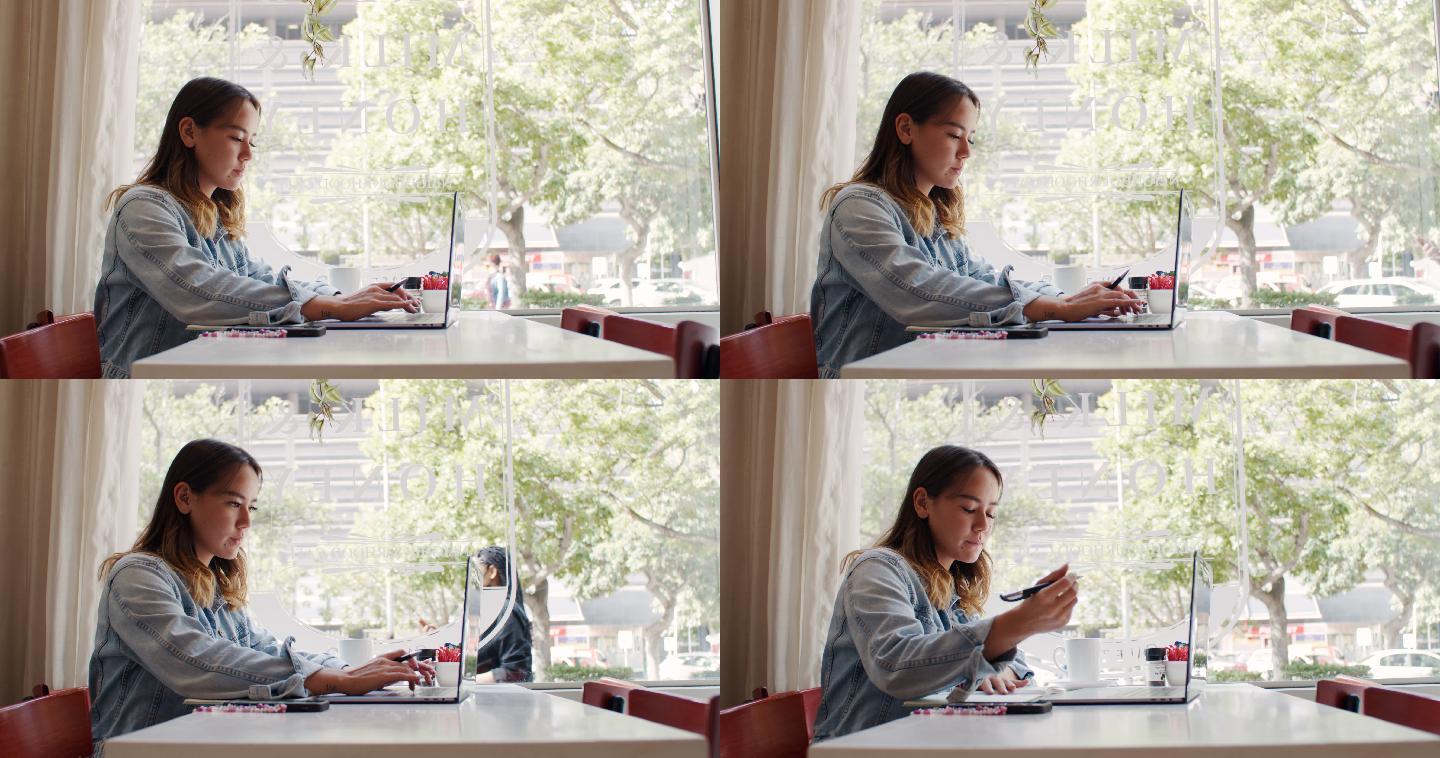 4k视频，一位年轻迷人的女士坐在咖啡馆里使用笔记本电脑