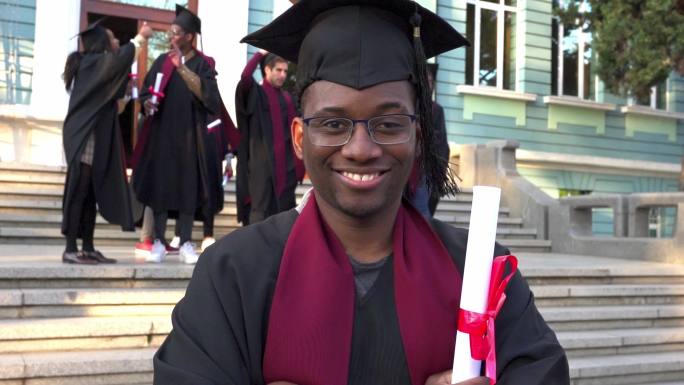 一位面带微笑的毕业生自豪地在大学台阶上展示他的证书