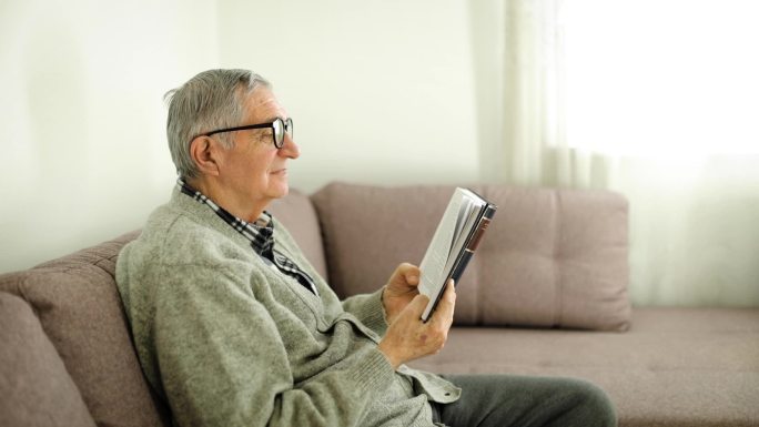 一个男人坐在客厅的沙发上看书。家庭老年生活。