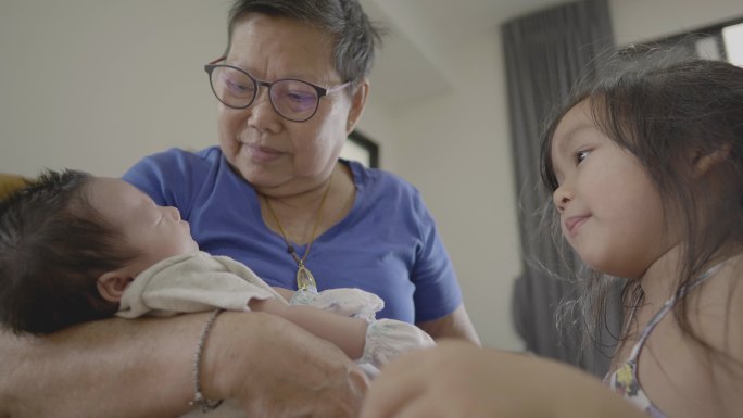 快乐的亚洲老奶奶抱着一个新生的家庭成员。坠入爱河。