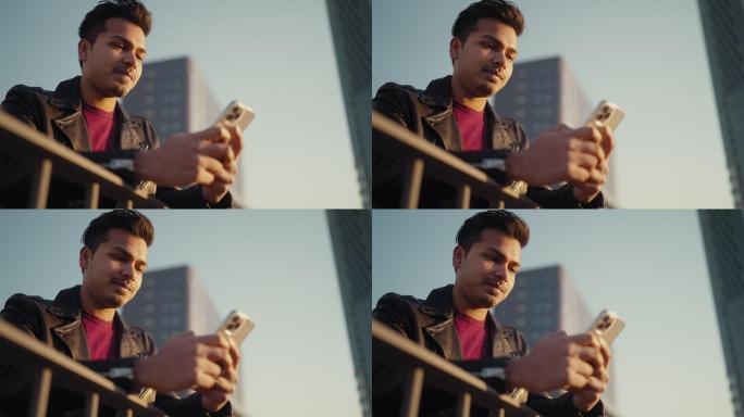 年轻英俊的印度男子在城市使用智能手机