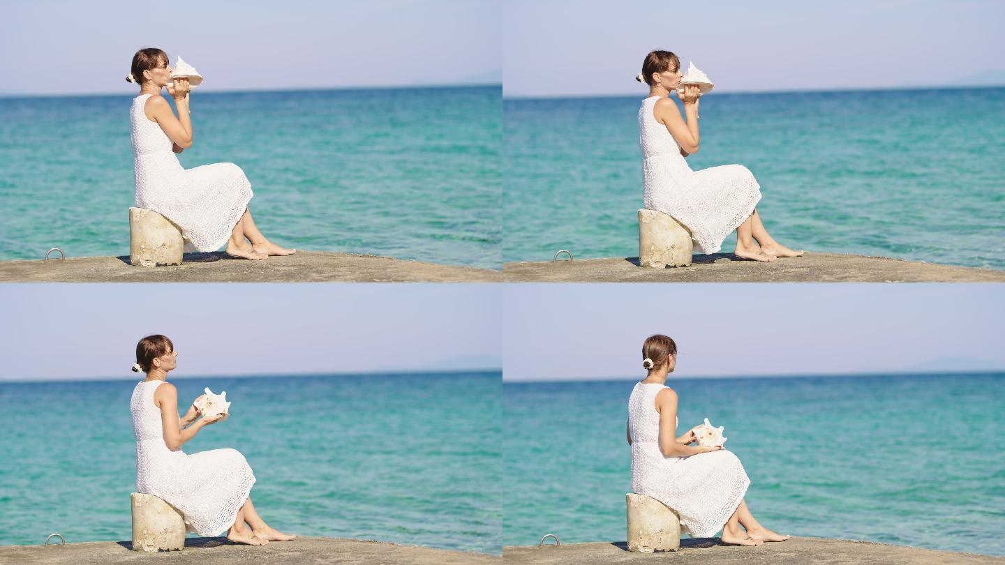 坐在海滩上的一个码头上，斯洛莫年轻女子对着海螺壳吹气