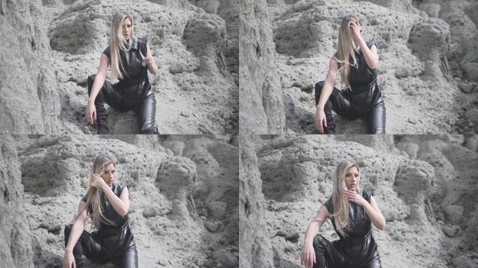 穿着黑色衣服，坐在外面的岩石上，头发上有风的美丽女性