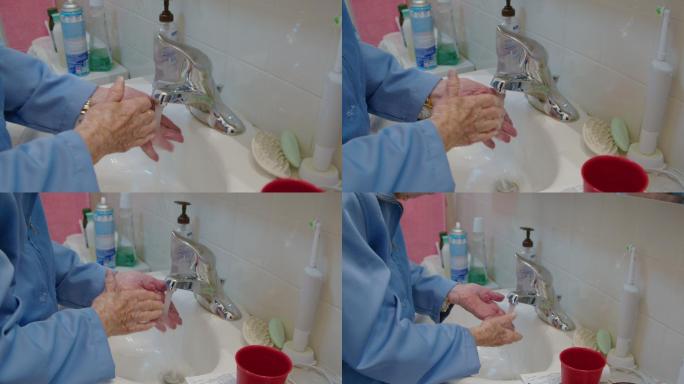 一位100岁的老妇人在家里凌乱的浴室水槽里洗手