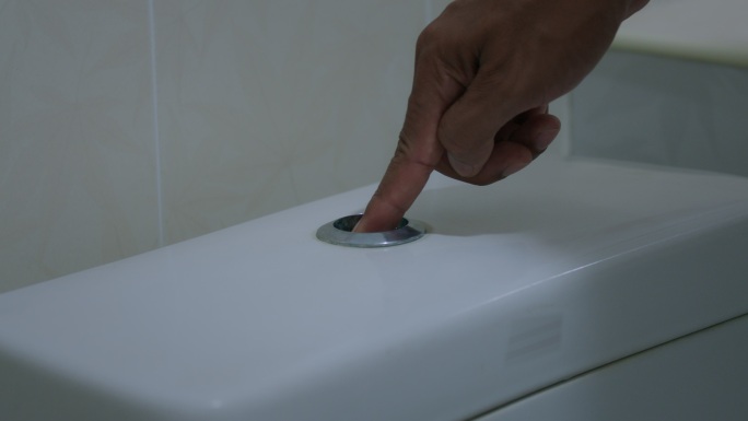 特写镜头：男用手指按浴室中的双按钮厕所冲洗。