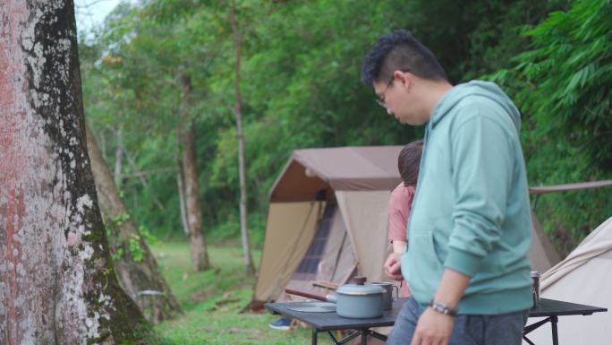 特写亚洲华人中年夫妇早上露营时煮开水准备咖啡