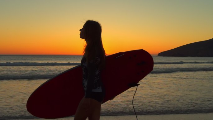 海滩上美丽的日落景色和一个女孩看着橙色的天空