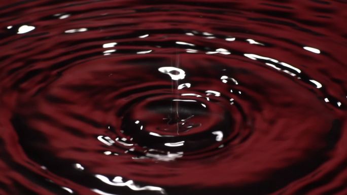 慢动作：许多水滴滴入红色水中。