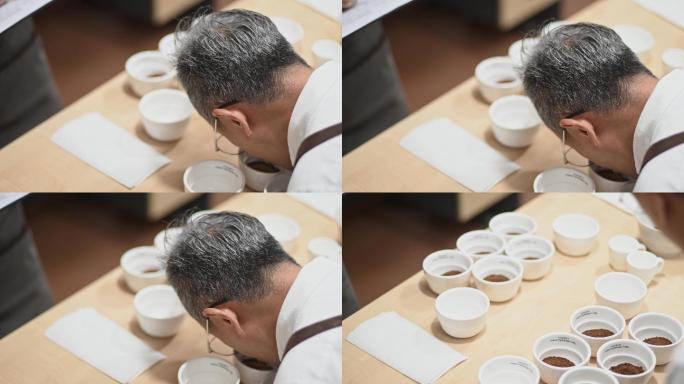 high angle view专业亚裔中国咖啡师品级师在咖啡杯上弯腰近距离闻咖啡