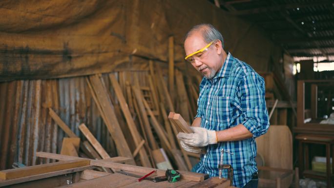 活跃的老年木匠在闲暇时间与木材一起工作。