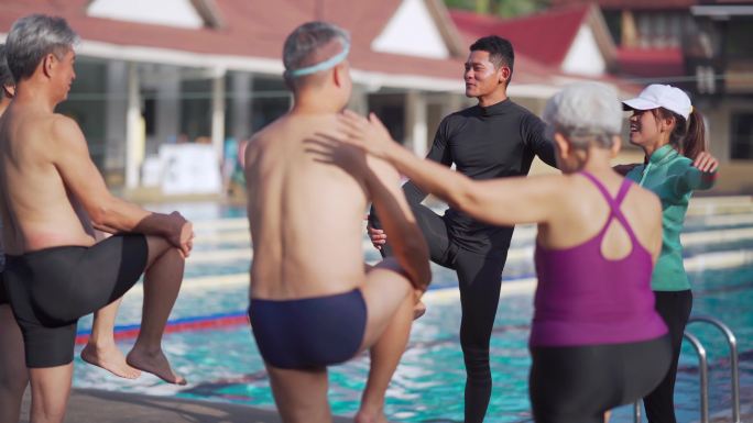 亚裔中国高中生游泳课前在泳池边向游泳教练学习热身运动