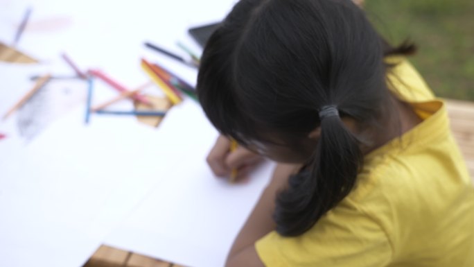 兄弟姐妹用彩色铅笔在纸上画卡通的场景，教育背景库存