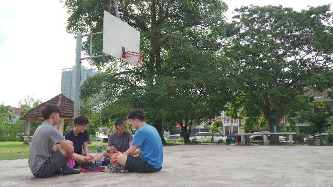 亚洲中国青少年篮球运动员赛后与朋友坐在球场上放松