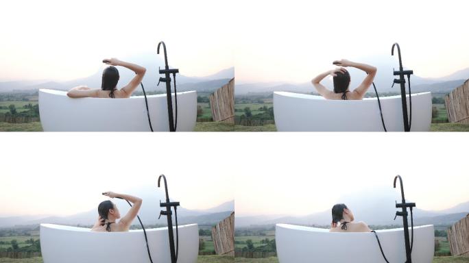 亚洲女性在户外放松，浴缸前有山景。淡季旅行