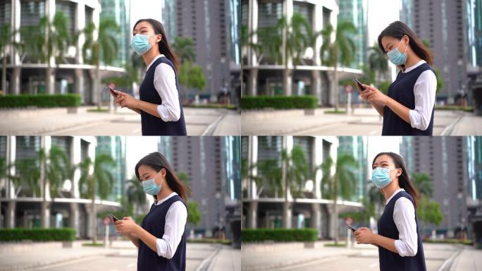 一名戴着防护面罩并使用智能手机的亚裔中国女性
