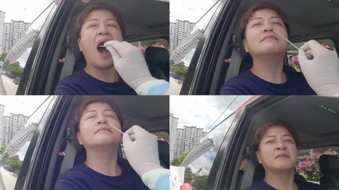 第一人在停车场观看户外场景亚裔中国女医生戴着PPE从患者冠状病毒测试中取鼻拭子。防护套间的医务人员正
