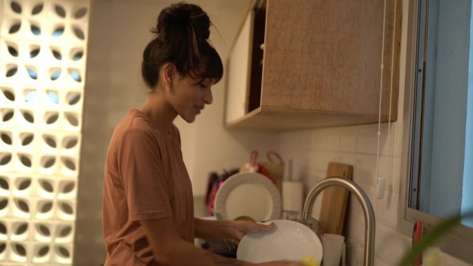 快乐的年轻女子在家洗碗