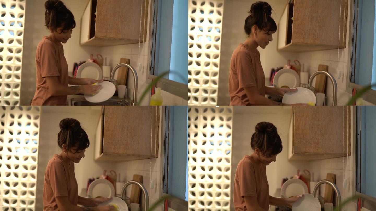 快乐的年轻女子在家洗碗