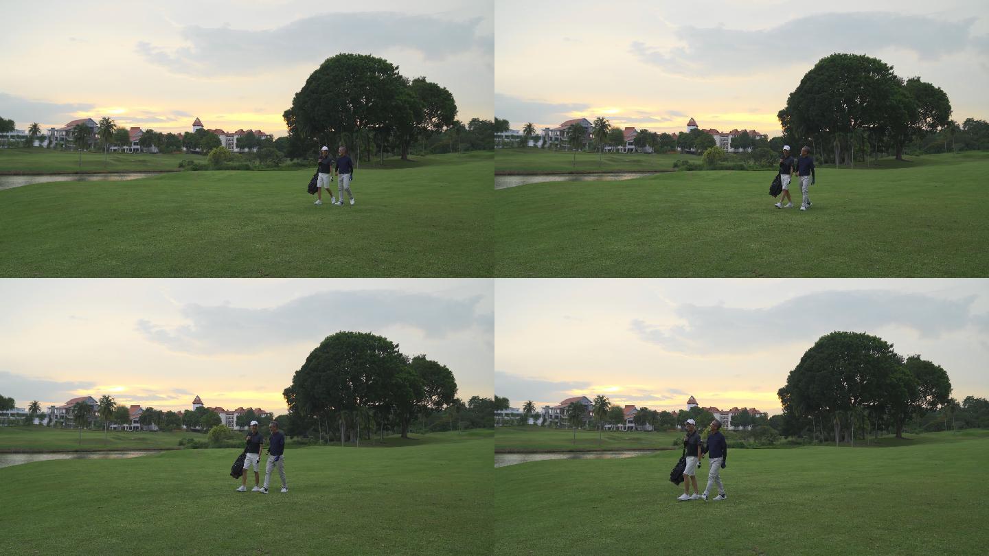 亚洲华人父子高尔夫球手日落时在高尔夫球场散步、谈笑风生