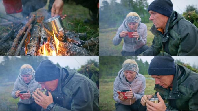男女野外生存专家坐在营火旁喝茶