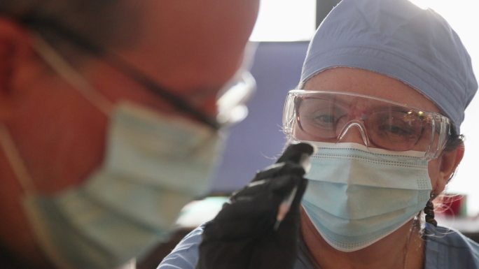 女性卫生工作者在上门拜访期间注射流感疫苗的特写镜头