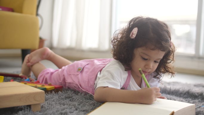 小女孩在书上画画宝宝小女孩趴在地上画画写