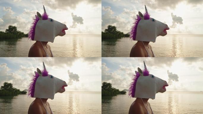 戴着独角兽面具的女子在海边欣赏日落
